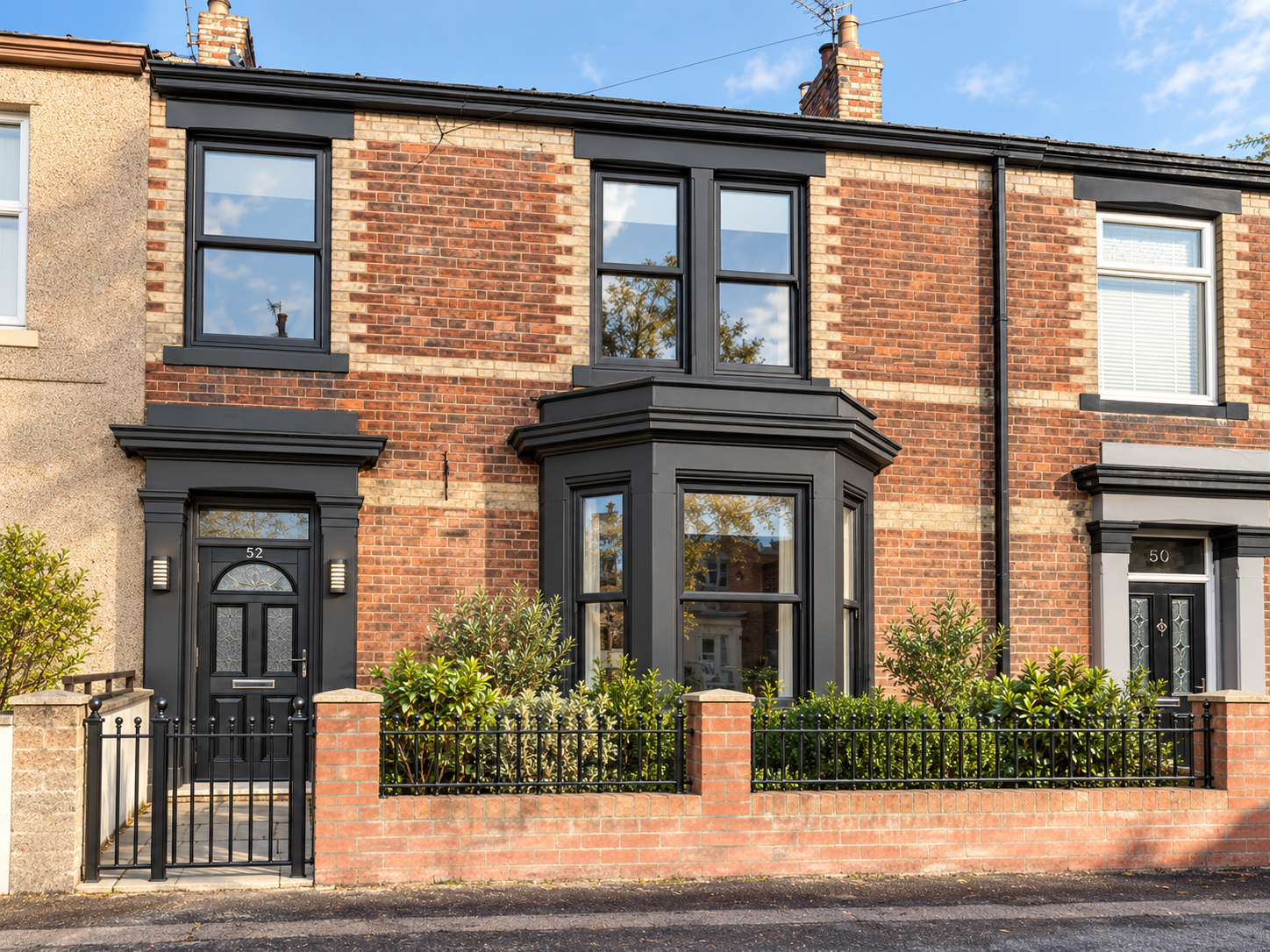 Calder Green brick townhouse with black window details, landscaped frontage and black metal fence in Jarrow